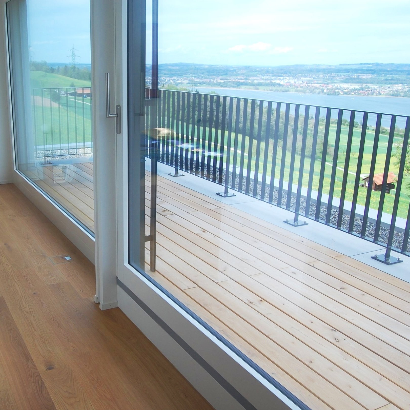 Terrassenholz vor einer Glasschiebetür mit Seeblick