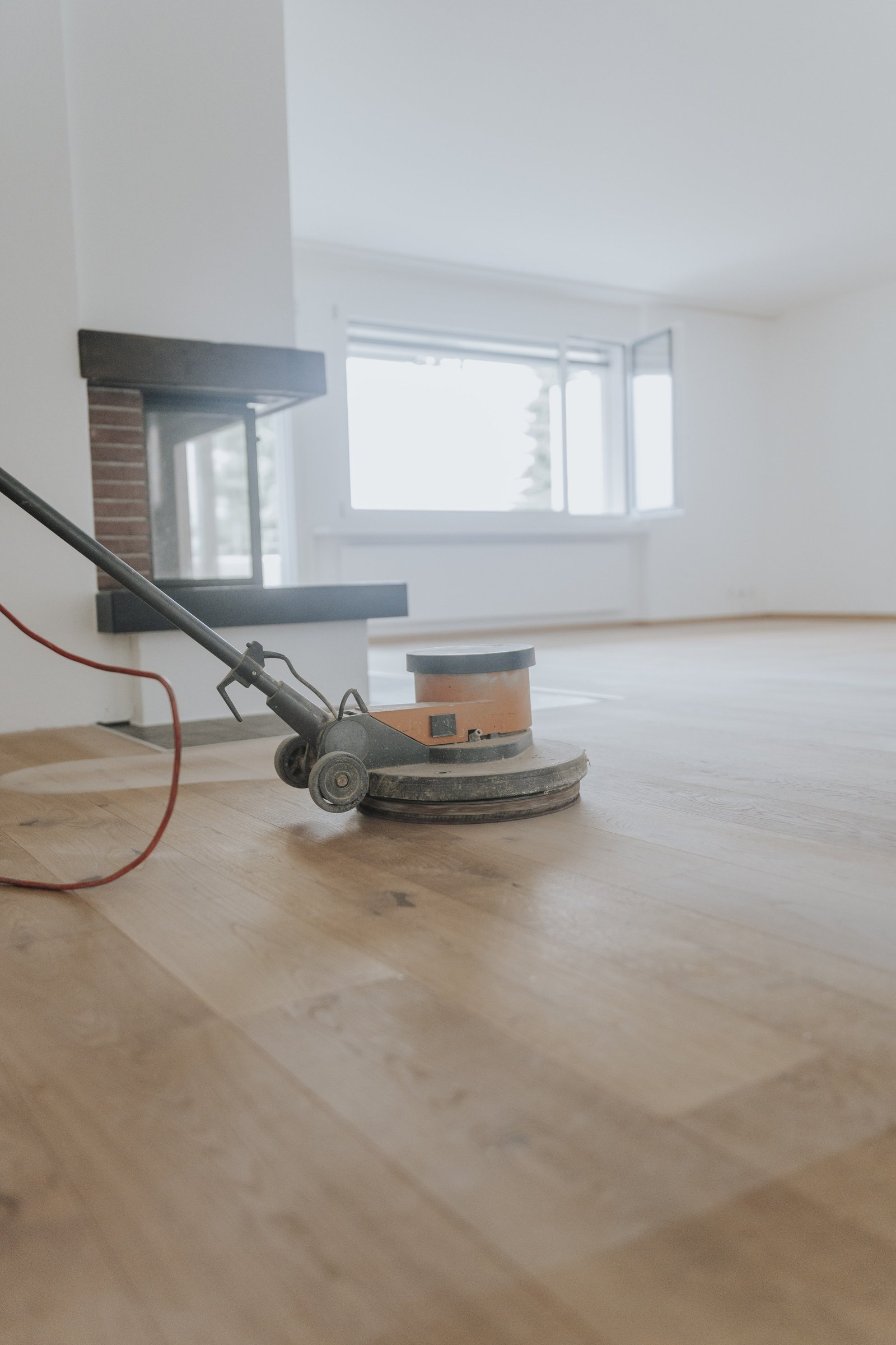 Parkett wird in einem Wohnraum mit Kamin geschliffen